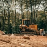 Trator de esteira em operação sobre terreno de obra, com o material rodante visível