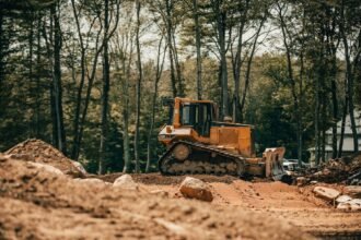 Trator de esteira em operação sobre terreno de obra, com o material rodante visível