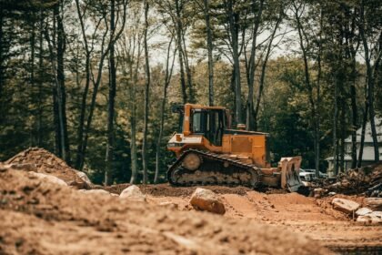 Trator de esteira em operação sobre terreno de obra, com o material rodante visível