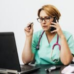 Médica com estetoscópio trabalhando em laptop no consultório, usando IA para médicos
