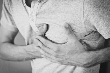 Sintomas de infarto feminino e masculino: mulher segurando o peito com dor no peito