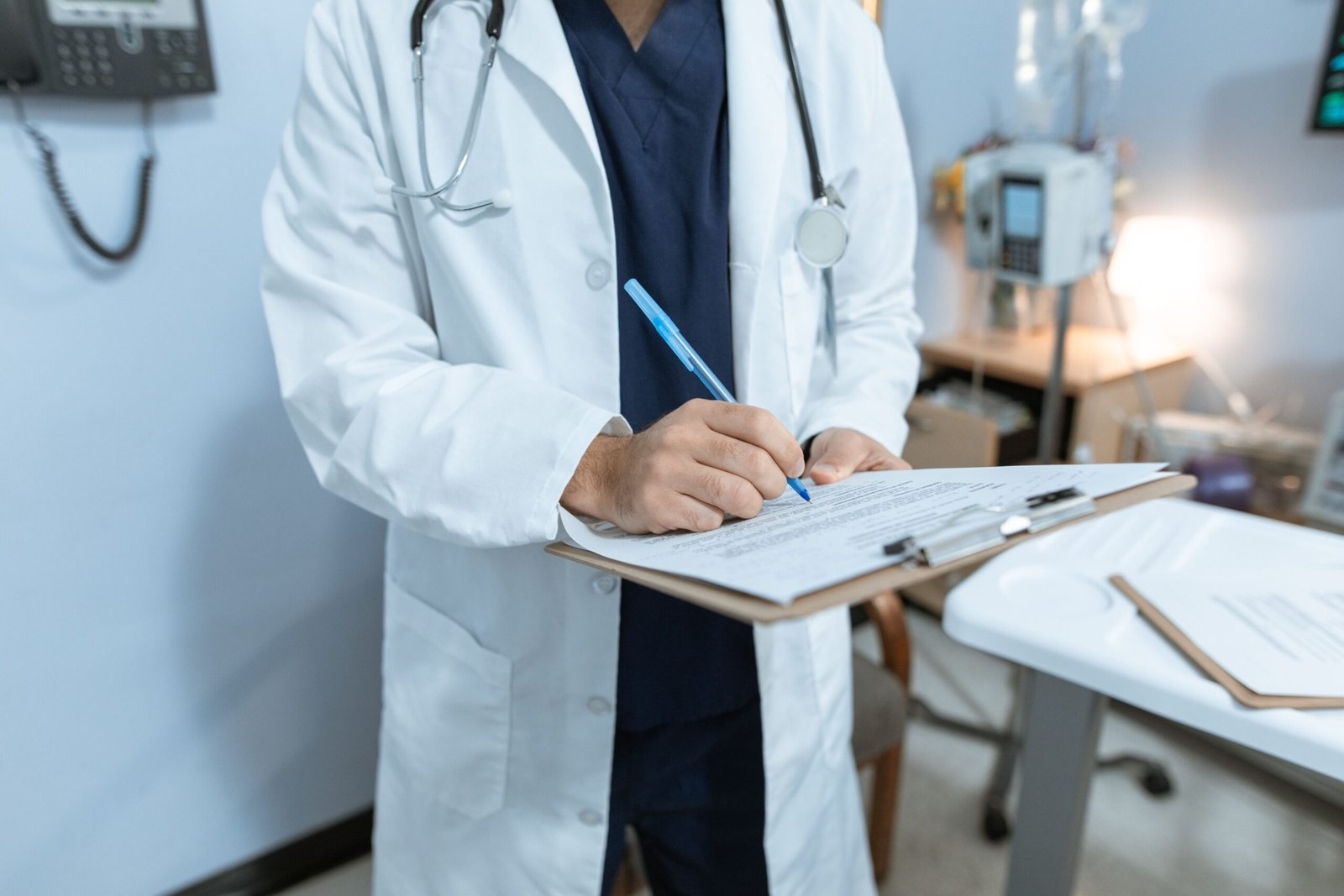 Médico de jaleco preenchendo atestado médico em prancheta, representando a emissão de um atestado médico rápido